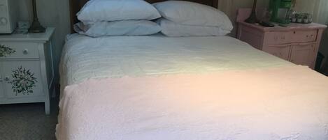 A neatly made bed with white bedding in a room with a wooden headboard.