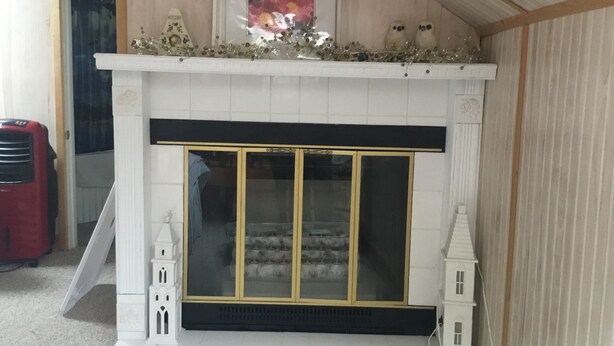 A fireplace with a white mantel, a framed picture above it, and two small decorative figures on either side. - Serenity Room located inside the Ivory Mansion
 (L'Anse)