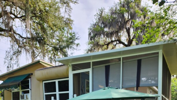 Una casa con una veranda coperta, una scala e una panchina in legno.
