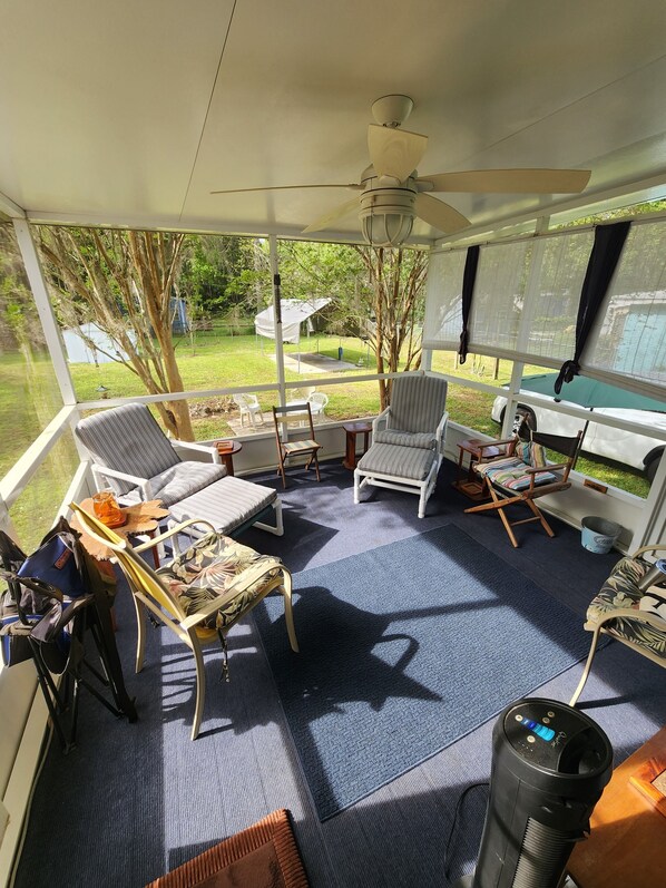 A covered outdoor seating area with a ceiling fan, multiple chairs, a table, and a view of the backyard. - Affordable Old Homosassa! Close to the action and the boat ramp! (Homosassa)