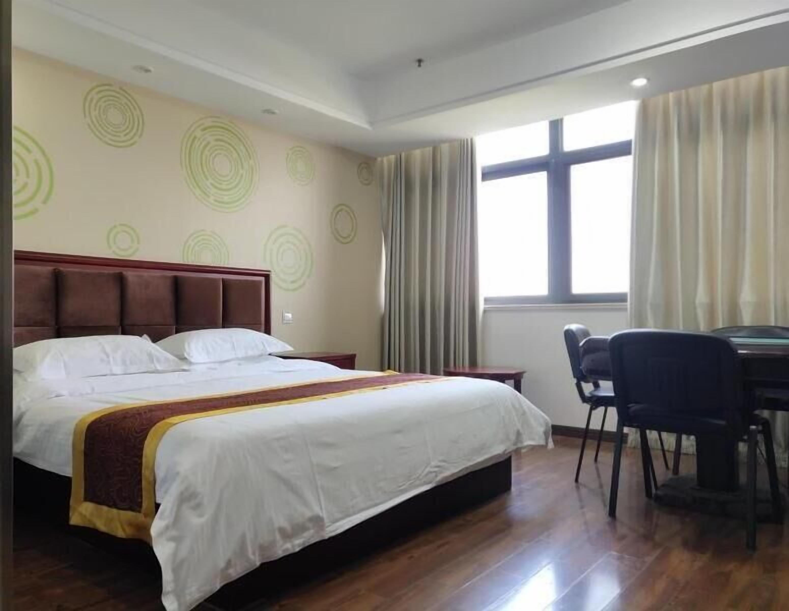 A hotel room with a bed, a desk, and a chair.