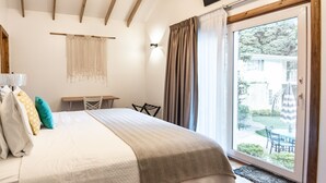 Une chambre à coucher avec un lit, un téléviseur fixé au mur, une table et une vue sur l’extérieur grâce à une porte coulissante.
