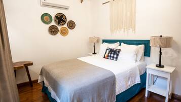 Un dormitorio con cama, mesitas de noche, aire acondicionado de pared y placas decorativas.