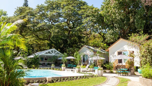 Un espace piscine doté d’une terrasse en bois, de coins salon extérieurs et d’une végétation luxuriante.