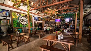 Un restaurant intérieur avec des tables et des bancs en bois, un coin bar et une fresque murale.