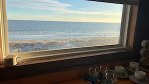 Vista del océano a través de una ventana, con una mesa de madera al frente.