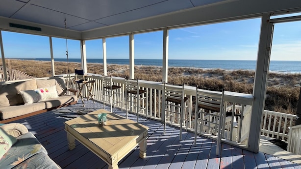 Una terraza techada con vista a la playa, un sofá y una mesa.