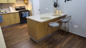 A kitchen with wooden cabinets, a stove, and a small island with stools.