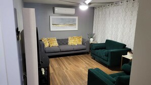A living room with a grey sofa, a green armchair, and a wooden floor.
