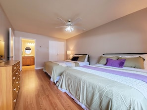 A bedroom with two beds, a ceiling fan, a bathroom with a vanity, and a wooden dresser. - Condo at Bryce Resort (Mount Jackson)