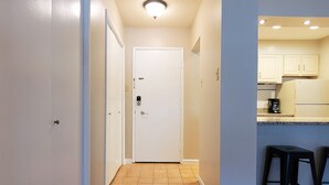 Un couloir avec un plancher en bois, des murs blancs et une porte blanche au fond.