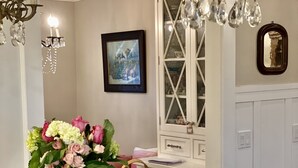 A dining table with a vase of flowers, a fruit basket, and a tote bag labeled "LOCAL REGENERATIVE BIODIVERSE." - OCEAN & CITY VIEWS 1920s Monthly, RIVIERA HOME, 2 QUEEN BEDS, WALK TO STATE ST (Santa Barbara)