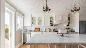A spacious kitchen with white cabinetry, a large marble island, and a chandelier. - OCEAN & CITY VIEWS 1920s Monthly, RIVIERA HOME, 2 QUEEN BEDS, WALK TO STATE ST (Santa Barbara)