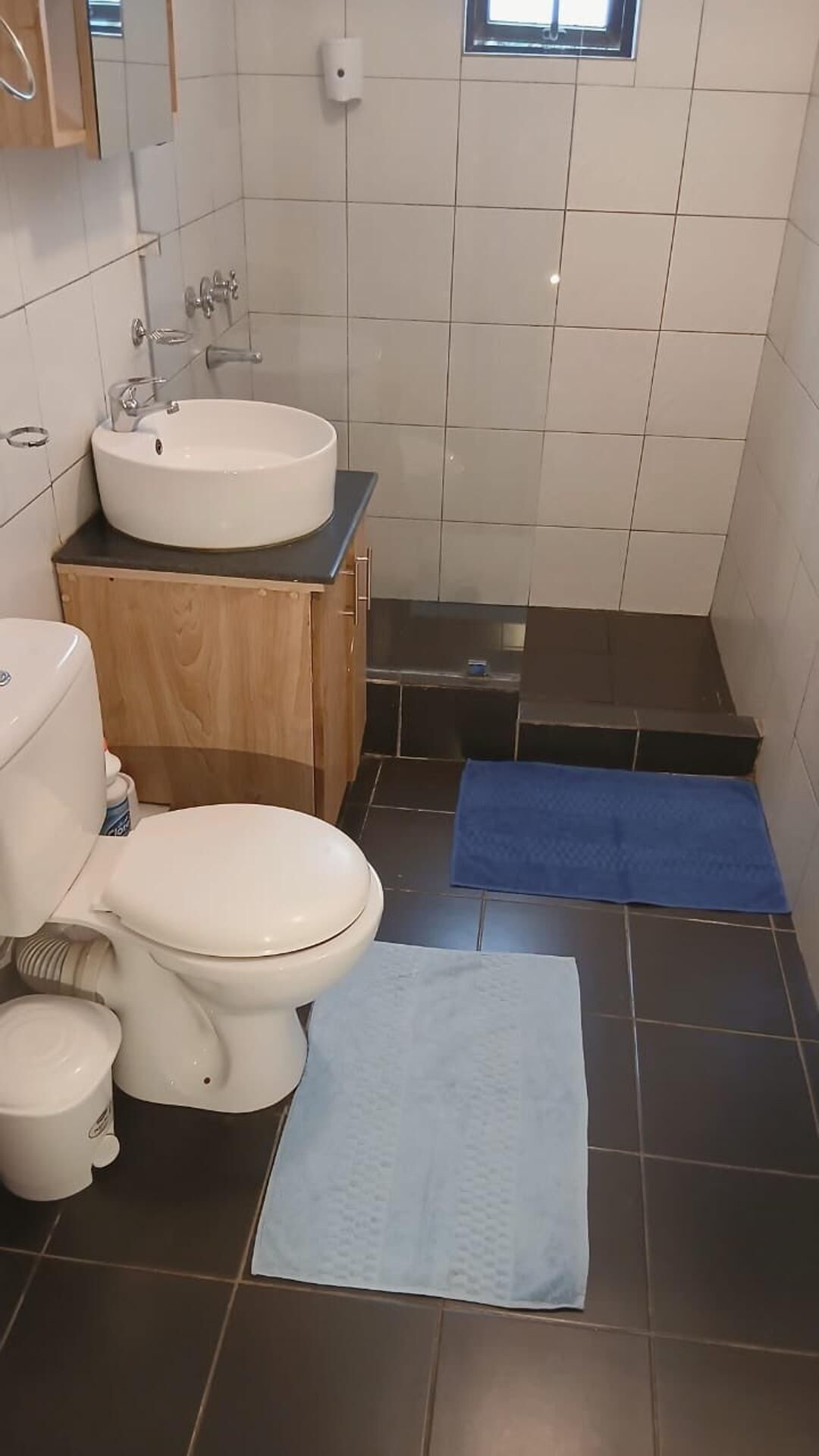 Casa de banho compacta com sanita branca, lavatório, banheira e zona de duche.