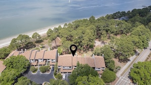 Une zone résidentielle côtière, avec une rangée de maisons, une plage et une vaste étendue d’eau.
