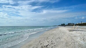 A beach with a sandy shore, a few lounge chairs, and a clear sky. - Salt Air, Sunlight, and Old Florida Flair (Longboat Key)