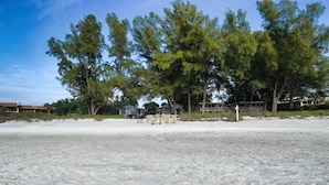 A beach with several lounge chairs and a white signpost. - 1BR Gulf Breezes & Old Florida Charm (Longboat Key)