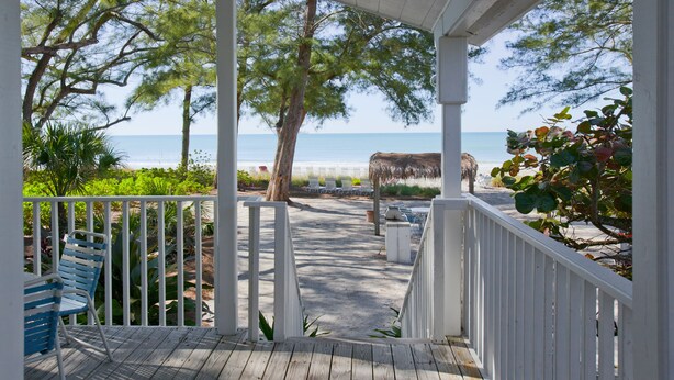 A wooden deck with white railings overlooking a beach. - Gulf-Front Charm with Old Florida Soul-2BR Cottage (Longboat Key)