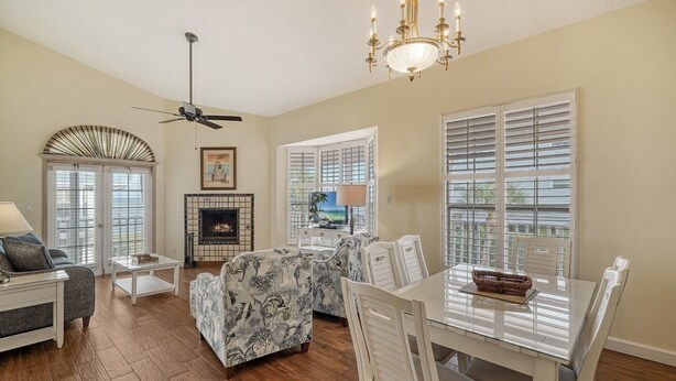 A spacious living room with a fireplace, a ceiling fan, and a dining area with a glass table. - 2BR Cottage Bayside Close to the Pool (Longboat Key)