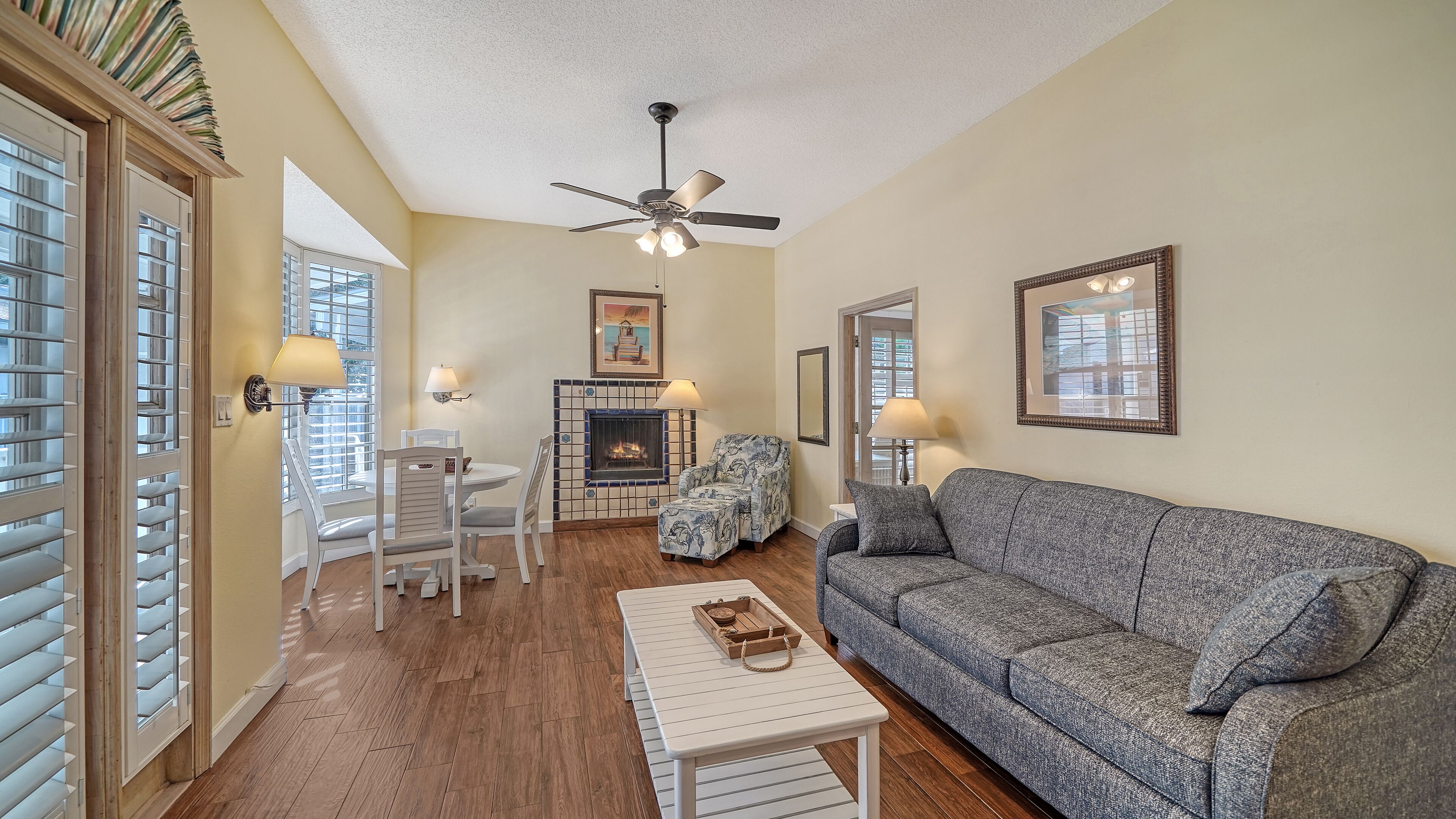 A living room with a fireplace, a sofa, a coffee table, and a dining area with chairs and a table.