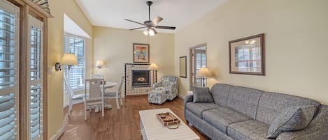 A living room with a fireplace, a sofa, a coffee table, and a dining area with chairs and a table.