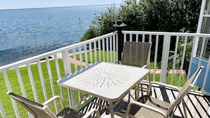 Een terras met een tafel en stoelen, met uitzicht op een waterpartij.