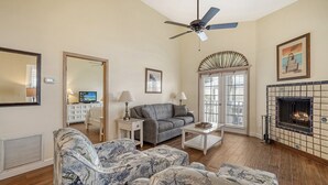 Un salon comprenant un canapé, des fauteuils, une table basse, une cheminée et un ventilateur de plafond.