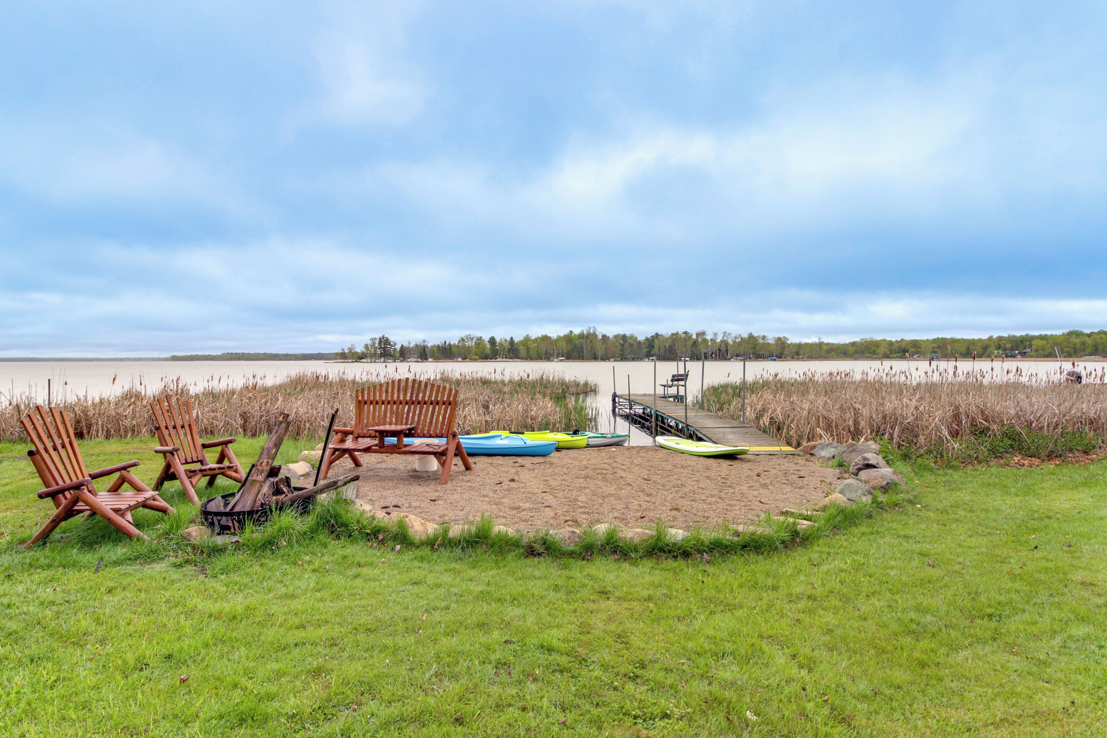 Une plage avec des chaises en bois, un canoë et un kayak.