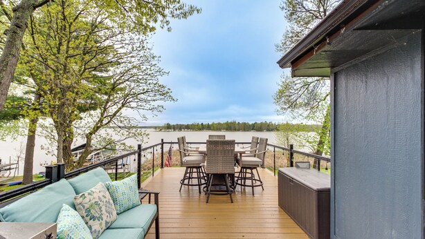 A wooden deck with a sofa and chairs, overlooking a lake. - 'Away at Moose Bay' Breezy Point Gem w/ Game Room (Breezy Point)