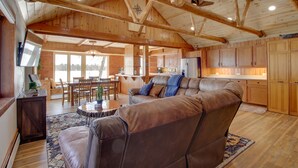 A spacious living area with a large leather sofa, wooden ceiling beams, and a kitchen in the background. - 'Away at Moose Bay' Breezy Point Gem w/ Game Room (Breezy Point)