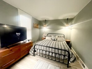 Relax in a stylish bedroom with a flat-screen TV, comfortable bed, and bedside lamps.