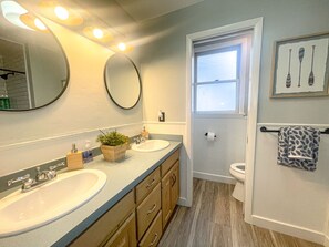 Bathroom features a dual sink vanity, wooden cabinetry, and a large mirror.