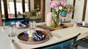 A dining area with a table set for two, featuring a vase of flowers, a candle, and a plate with a blue napkin. - Rare East Side-2 min walk to UWM-Garage-Lake Mich (Milwaukee)