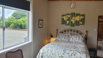 A bedroom with a bed, a chair, a window, a world map on the wall, and a ceiling light.