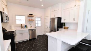 A modern kitchen with white cabinets, a black hexagonal floor, stainless steel appliances, and a central island.