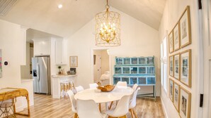 A spacious kitchen with white cabinetry, a stainless steel refrigerator, and a dining area with a white table and chairs. - A Modern luxury oasis on the plaza (Oklahoma City)