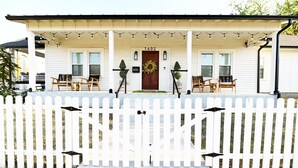 A white house with a porch, numbered 1602, featuring two chairs and a table. - A Modern luxury oasis on the plaza (Oklahoma City)