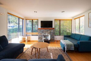 Una sala de estar con chimenea de piedra, un televisor de pantalla plana montado arriba y un sofá.