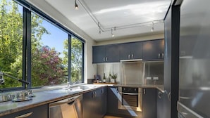 A modern kitchen with dark cabinets, stainless steel appliances, and a wooden floor. - Prime Location | 3 bedroom home | Unlimited WIFI (Queenstown)