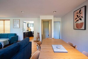 A modern living space with a dining area, a kitchen, and a seating area with a sofa and chairs. - Prime Location | 3 bedroom home | Unlimited WIFI (Queenstown)