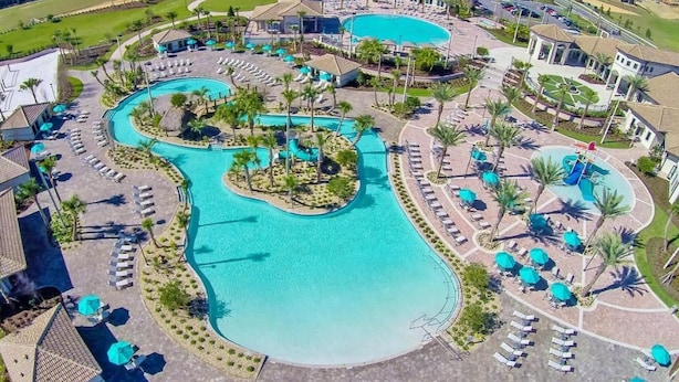 A resort with multiple swimming pools, sun loungers, and palm trees. - Luxury Champions Gate Condo, Resort-Style Retreat (Four Corners)
