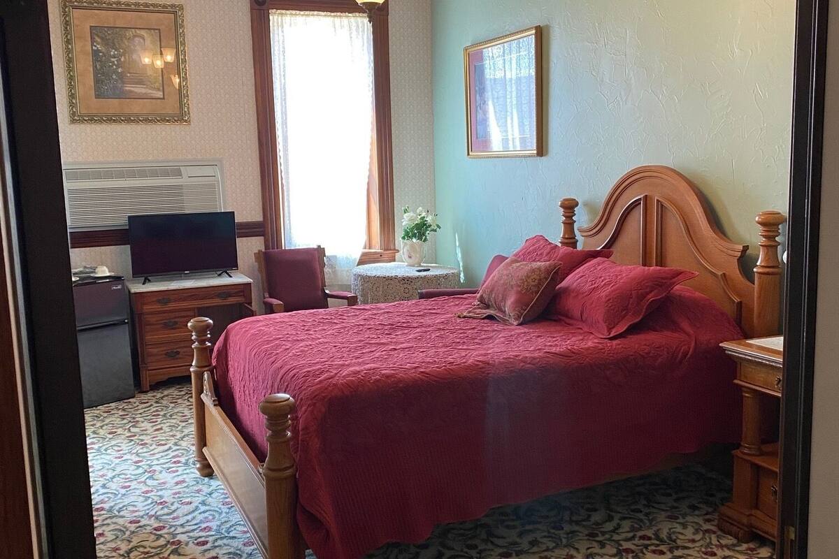 A bedroom with a wooden bed, a television, a desk, and a chair.