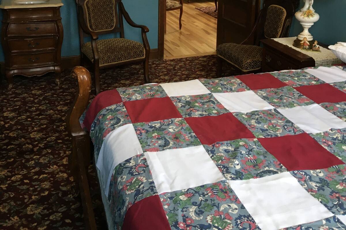 A bedroom with a wooden bed, a dresser, a mirror, a chair, and a lamp.