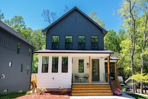 A two-story house with a front porch, a staircase, and a small outdoor seating area.