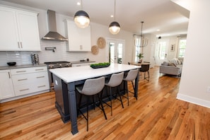 Enjoy meals in the central island kitchen with a stainless steel stove, island sink, and white cabinetry.