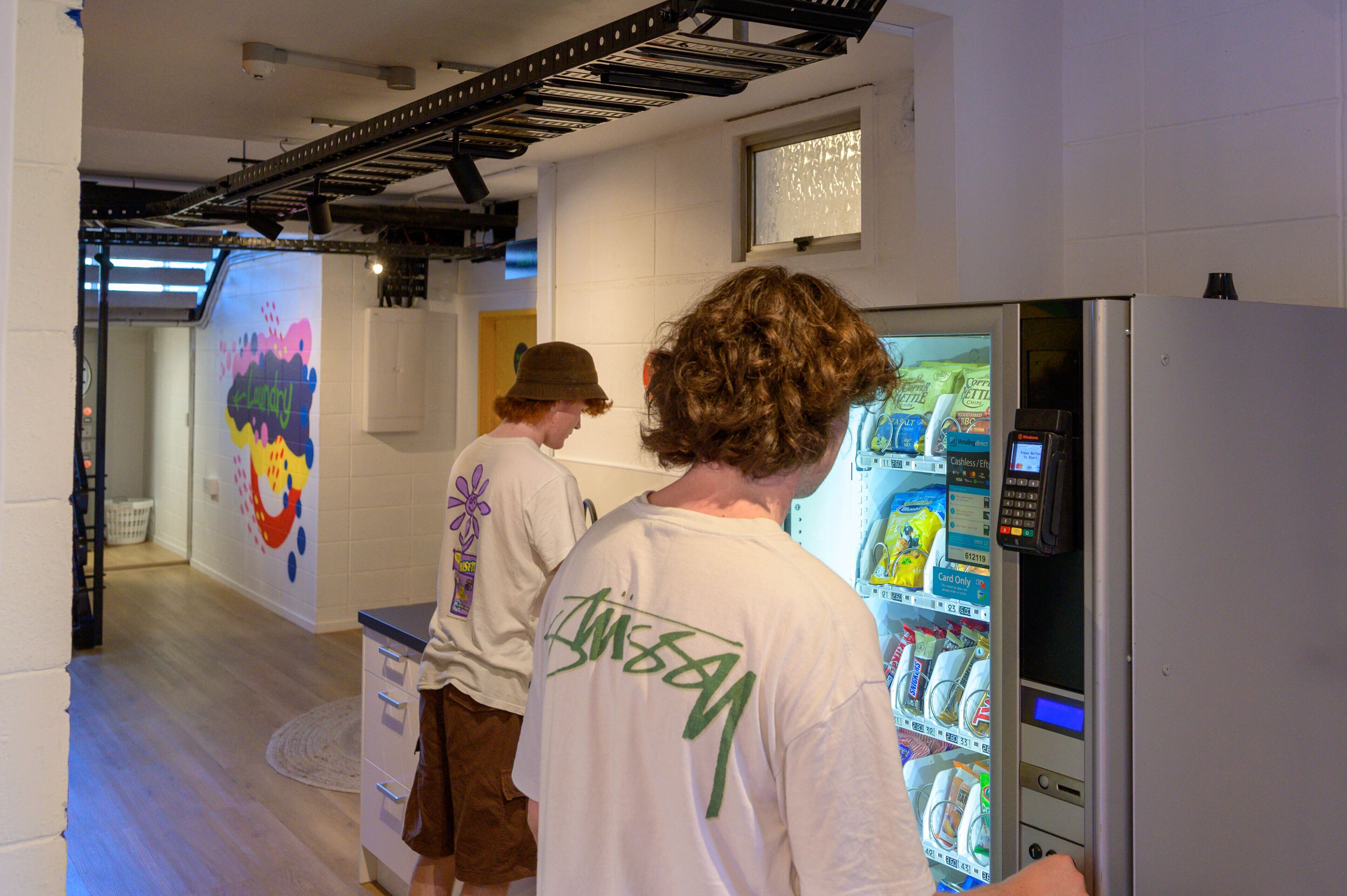 A room with a vending machine, a window, and a wall with colorful graffiti.