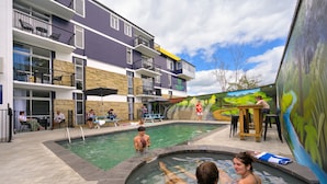 A pool area with a building in the background, outdoor seating, and a mural. - Urban Lounge Sleepery, SureStay Collection by BW (Rotorua)