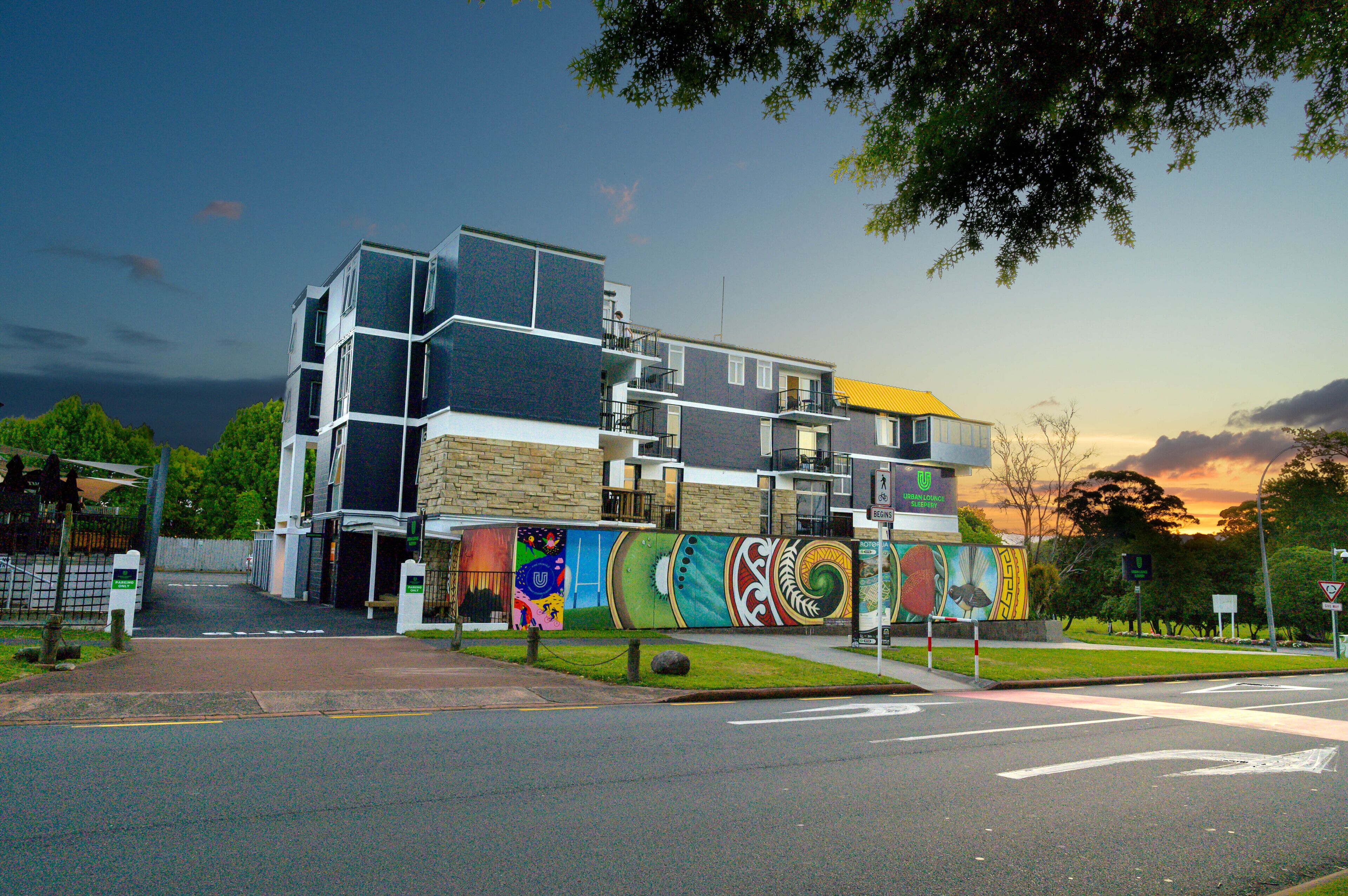 A modern building with a colorful mural on its facade, a multi-level structure, and a street view with a traffic light.