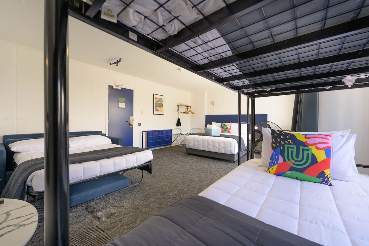 A dormitory room with bunk beds, a desk, and a chair.