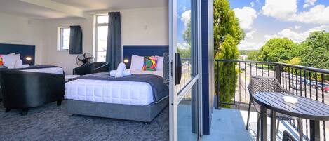 A hotel room with a bed, a sitting area, and a balcony with a table and chairs.